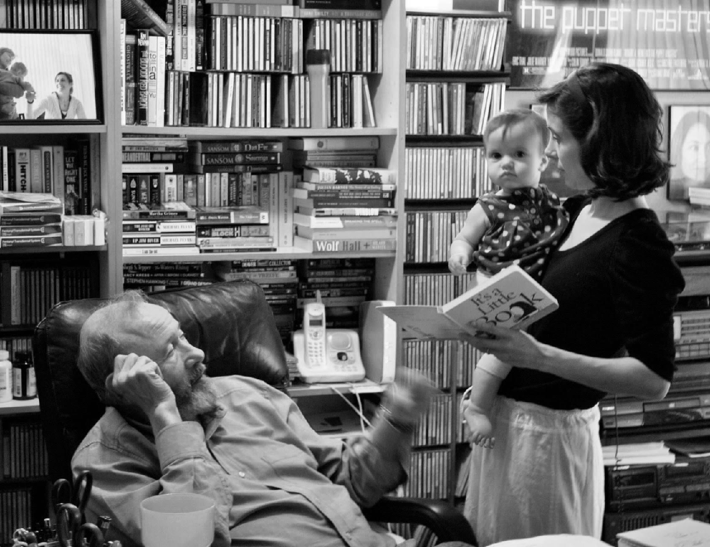 Leslie with her daughter and father in front of bookshelves